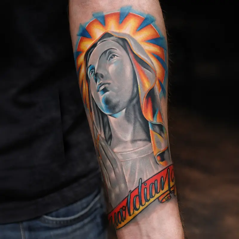 Color Madonna portrait forearm tattoo with radiant halo and script banner.
