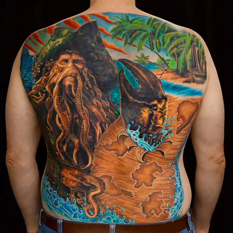 Full back Pirates of the Caribbean themed tattoo with ocean, island, and Davy Jones character.